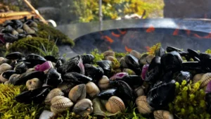 Frische Miesmuscheln und Venusmuscheln vor dem Grillfeuer, bereit zur Zubereitung.