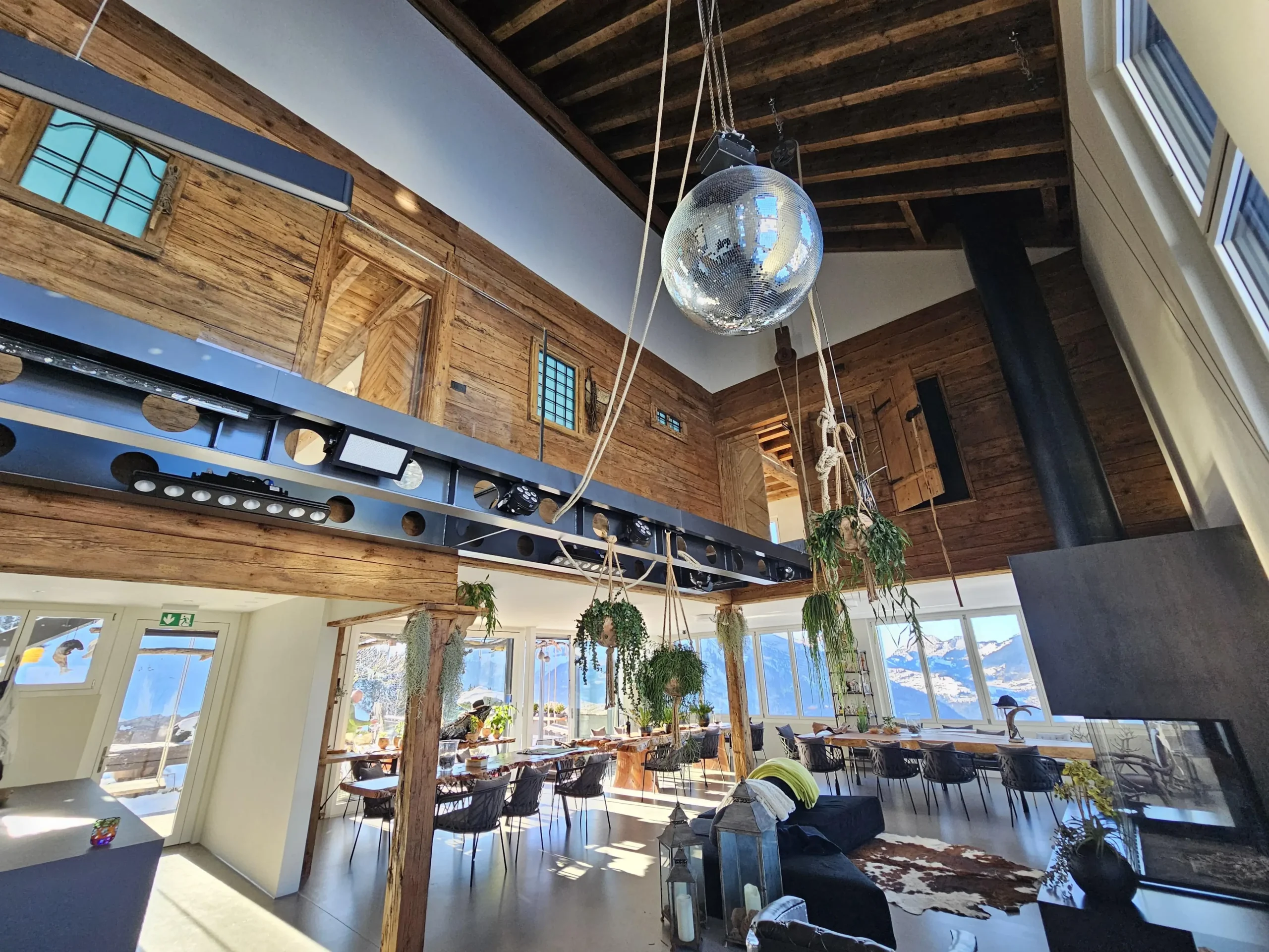 Modernes Eventlokal auf der Fronalp bei Mollis mit grosser Panoramaaussicht auf die Glarner Alpen, stilvollem Innenraum, Holz- und Stahlelementen sowie Discokugel – ideal für private Feiern und Firmenanlässe.